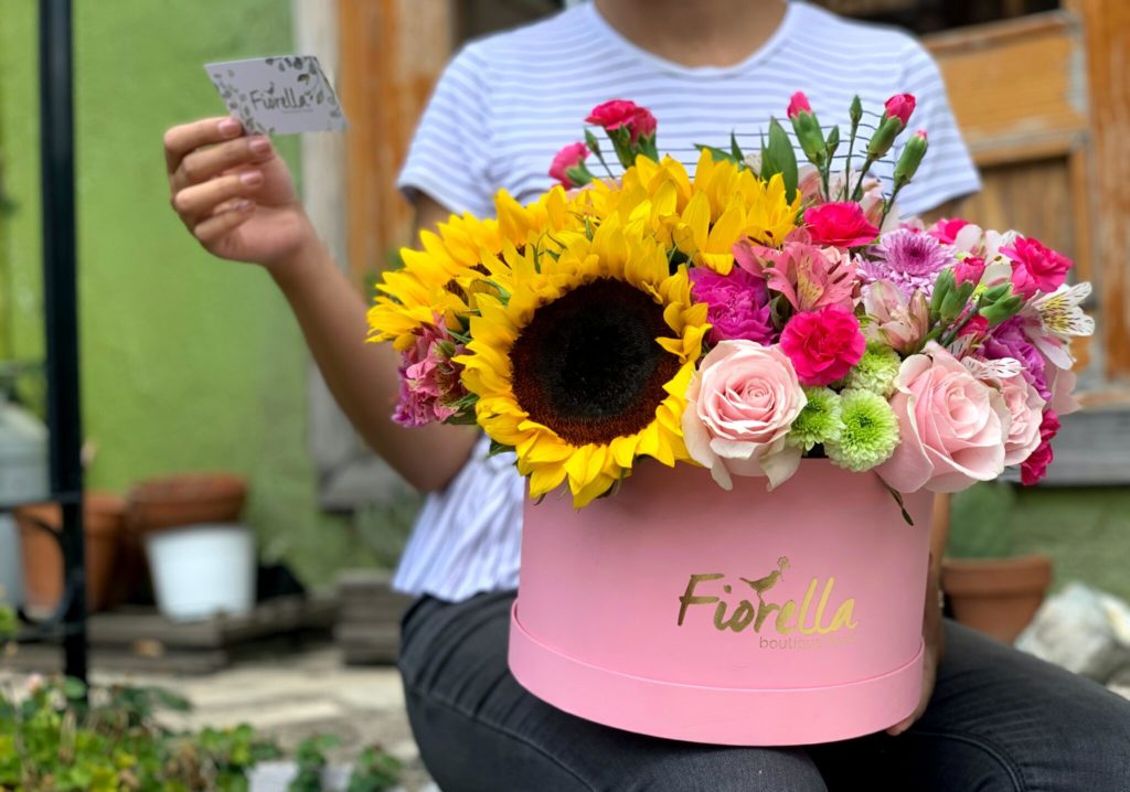 assorted-color petaled flowers in pink vase on woman's lap